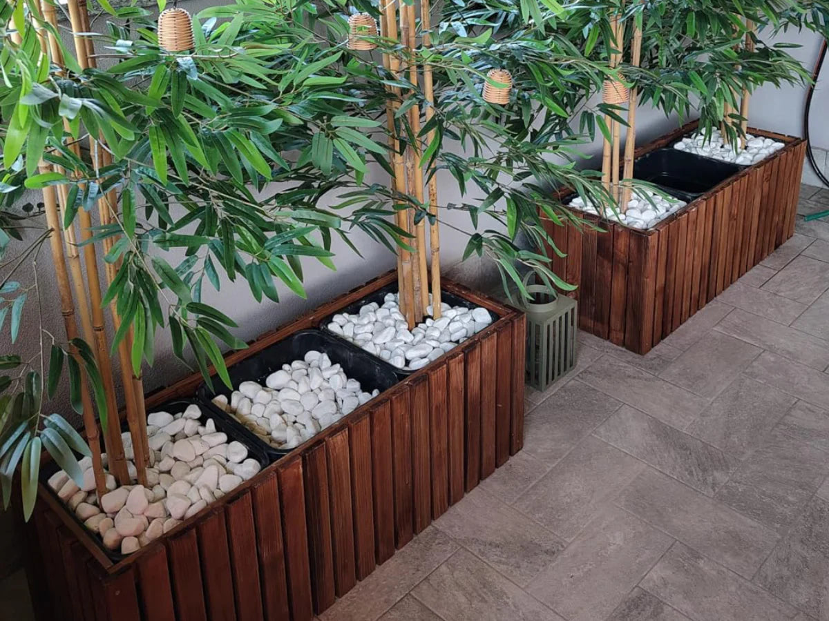 Drewniane donice z zielonymi roślinami i białymi kamieniami na tarasie