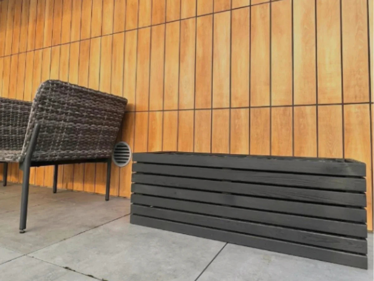 Czarna drewniana donica na tarasie przy ścianie z paneli, nowoczesny design ogrodowy