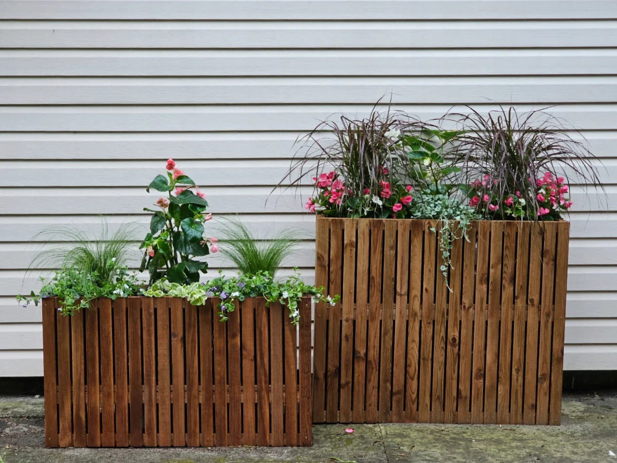 Drewniane donice ogrodowe z kwiatami i trawami na tle jasnej ściany, naturalny design